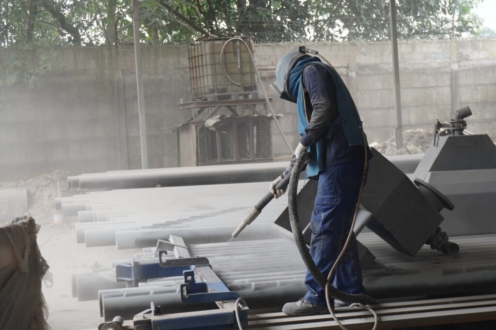 foto pekerja sandblasting menghilangkan karat di pipa pada proyek eltama coating